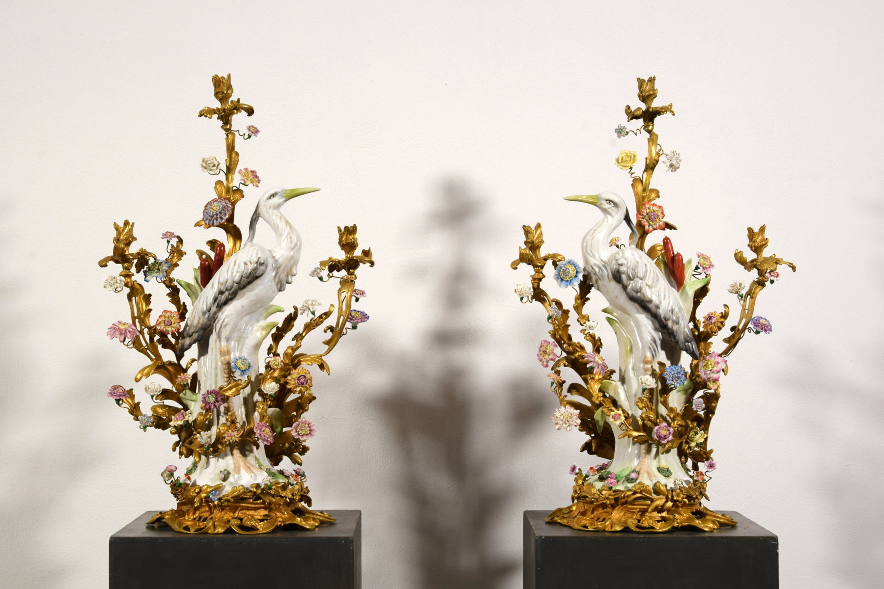  Coppia di grandi candelabri a tre luci in bronzo dorato con aironi e fiori in porcellana policroma, Francia, XIX secolo